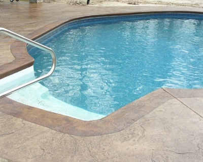 In-ground pool with stamped concrete pool deck.