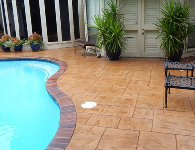 Brown stamped concrete pool surround with brick style edges.